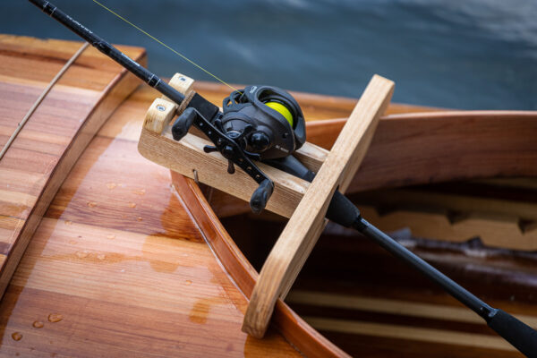 a wooden rod holder on a fishing canoe on the river