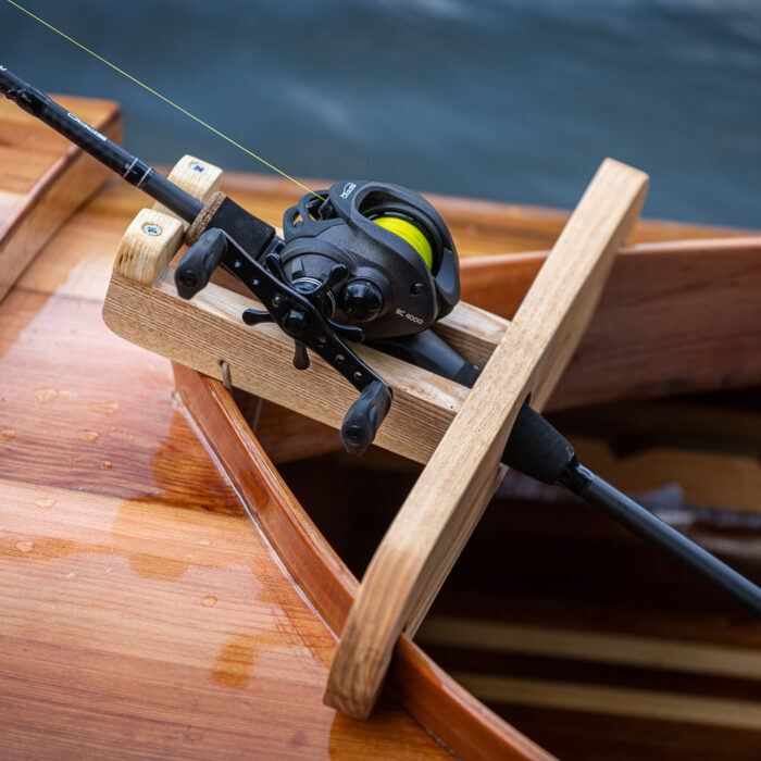 een houten viskano met een hengelhouder op de rivier